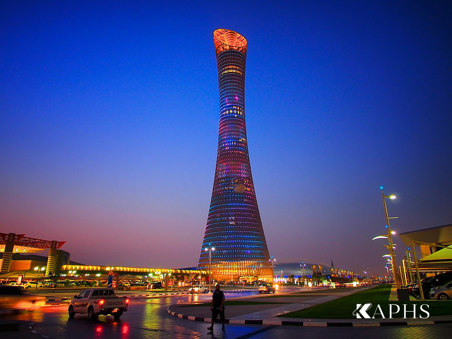 Aspire Tower lit at night, its architectural wire mesh façade glowing with integrated LEDs, Doha — KAPHS