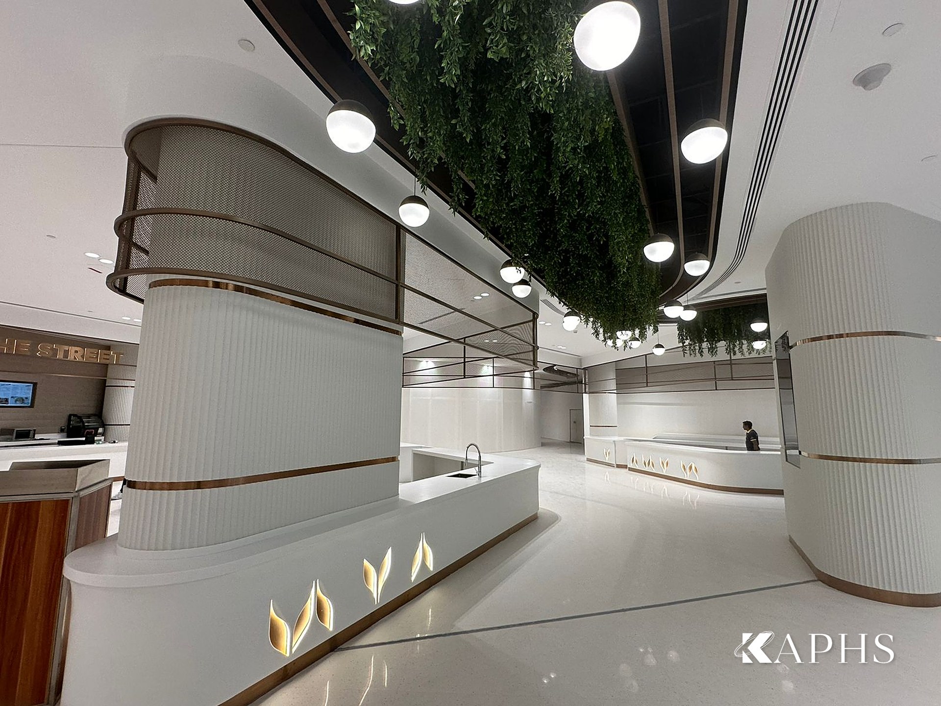 Curved bronze decorative wire mesh soffit over a food stall, DAFZA Food Court Dubai — KAPHS