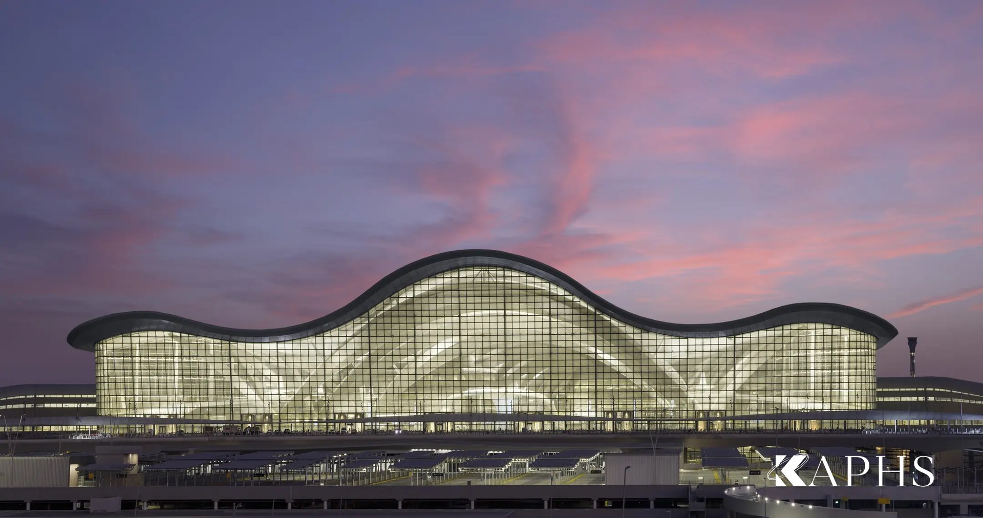 Zayed International Airport wave-roof terminal in NorthGlass jumbo glass at dusk, Abu Dhabi — KAPHS