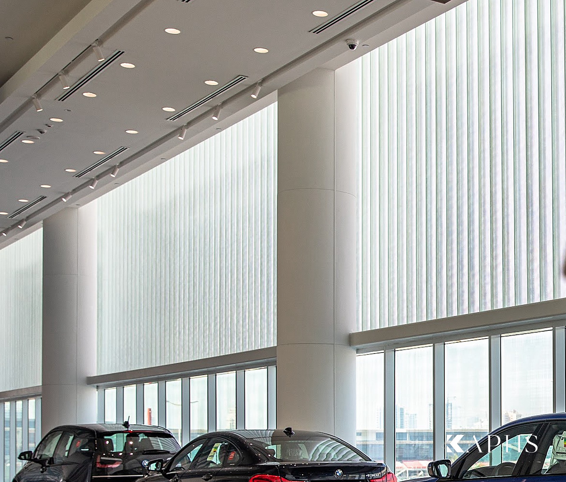 AGMC BMW showroom, Motor City — translucent U-channel glass wall behind the display cars, KAPHS