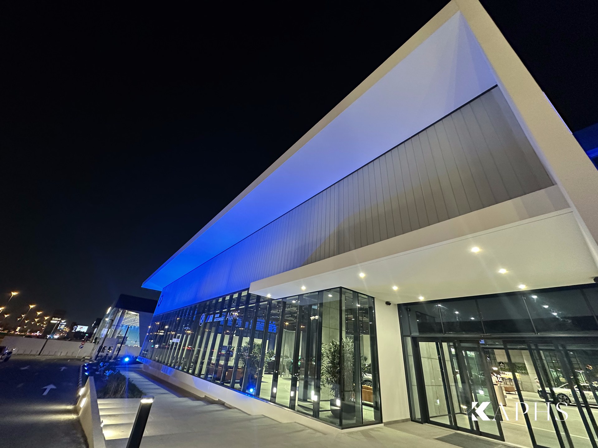 Entrance elevation of the AGMC BMW showroom, Sharjah — illuminated LINIT U-channel glass clerestory façade, KAPHS