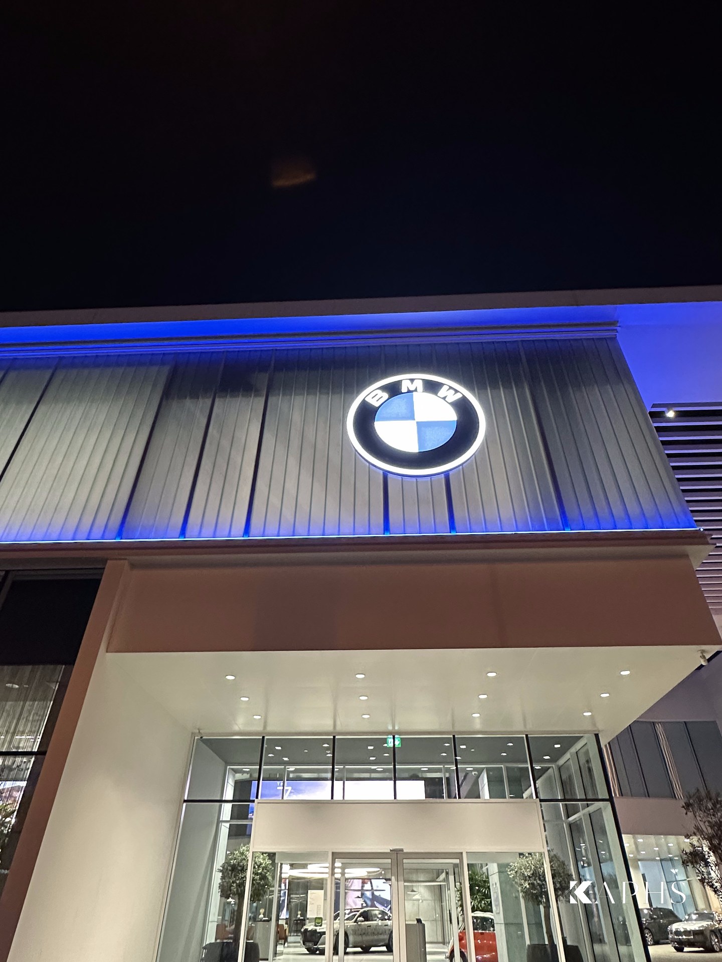 AGMC BMW showroom, Sheikh Zayed Road — close-up of the BMW roundel on the LINIT U-channel glass fascia, KAPHS