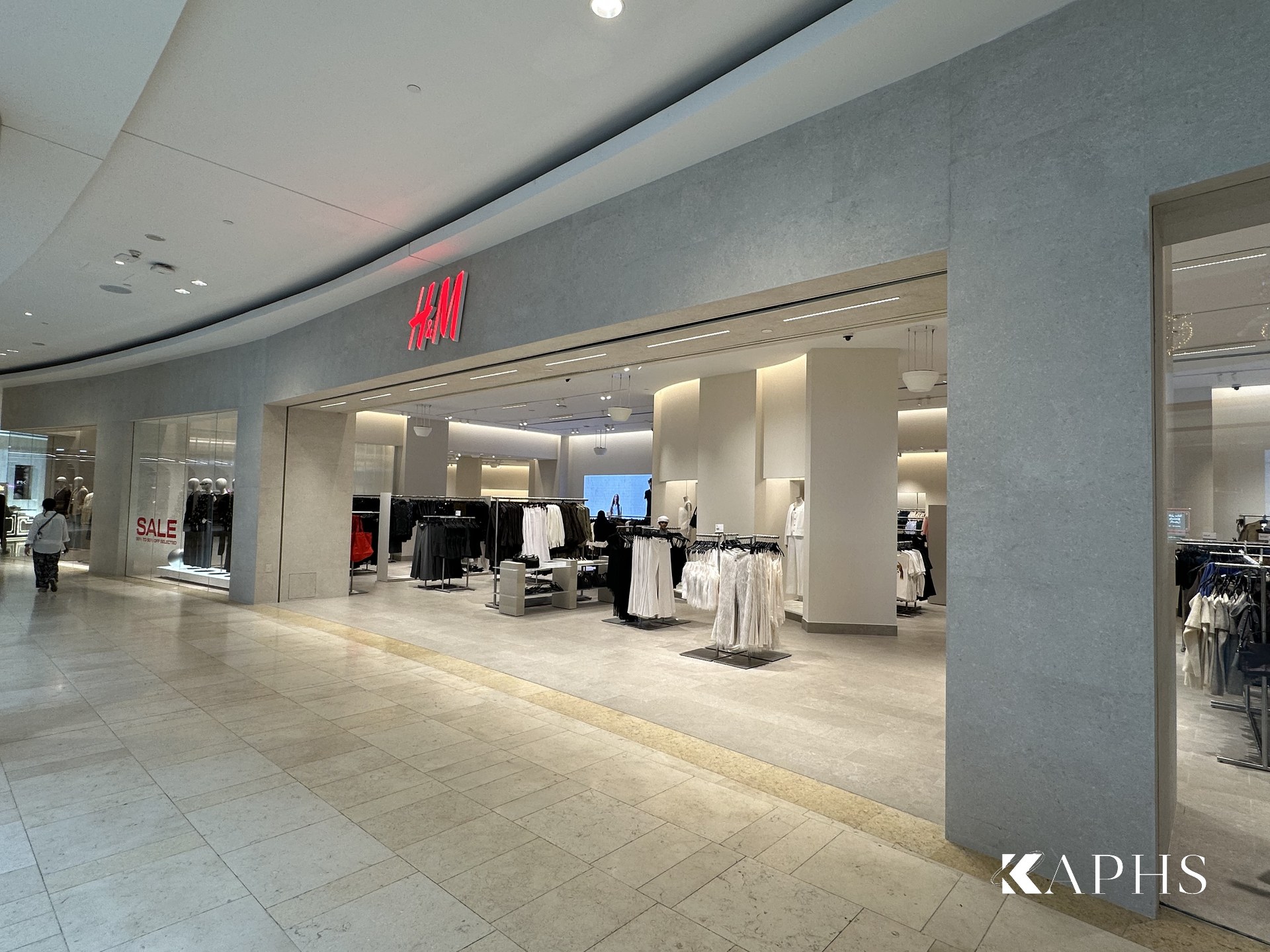 Store overview with backlit channel glass display bays, H&M Yas Mall — KAPHS